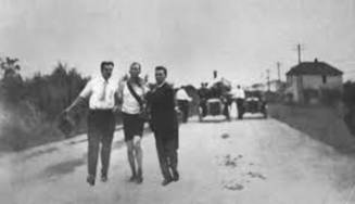 El ganador del maratón Thomas J. Hicks, andando y ayudado, para no caer al suelo